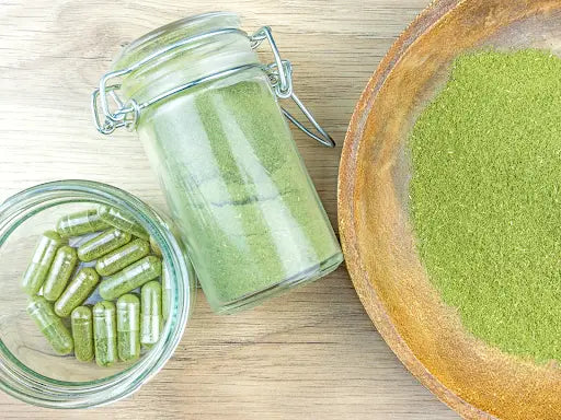 jar with green powder in middle, capsules to the left and bowl filled with green powder to the right