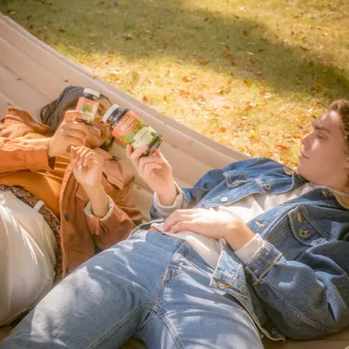 two people laying in hammock cheersing with bottles of red maeng da