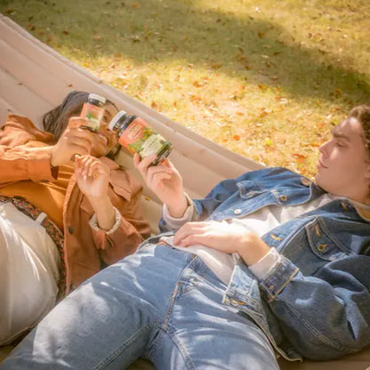 two people laying in hammock cheersing with bottles of red maeng da