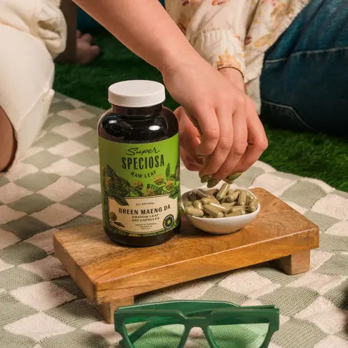 hands reaching into small bowl of green Maeng da kratom capsules